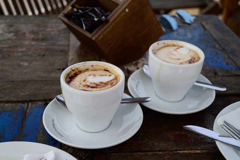 two cups of coffee on a table with silverware