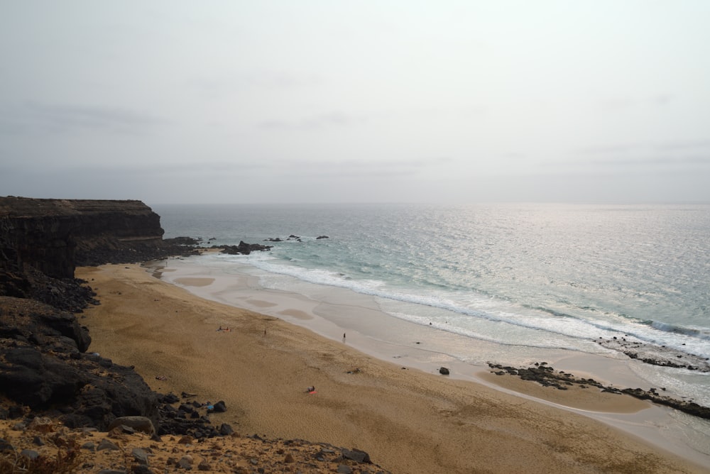 a sandy beach next to the ocean on a cloudy day