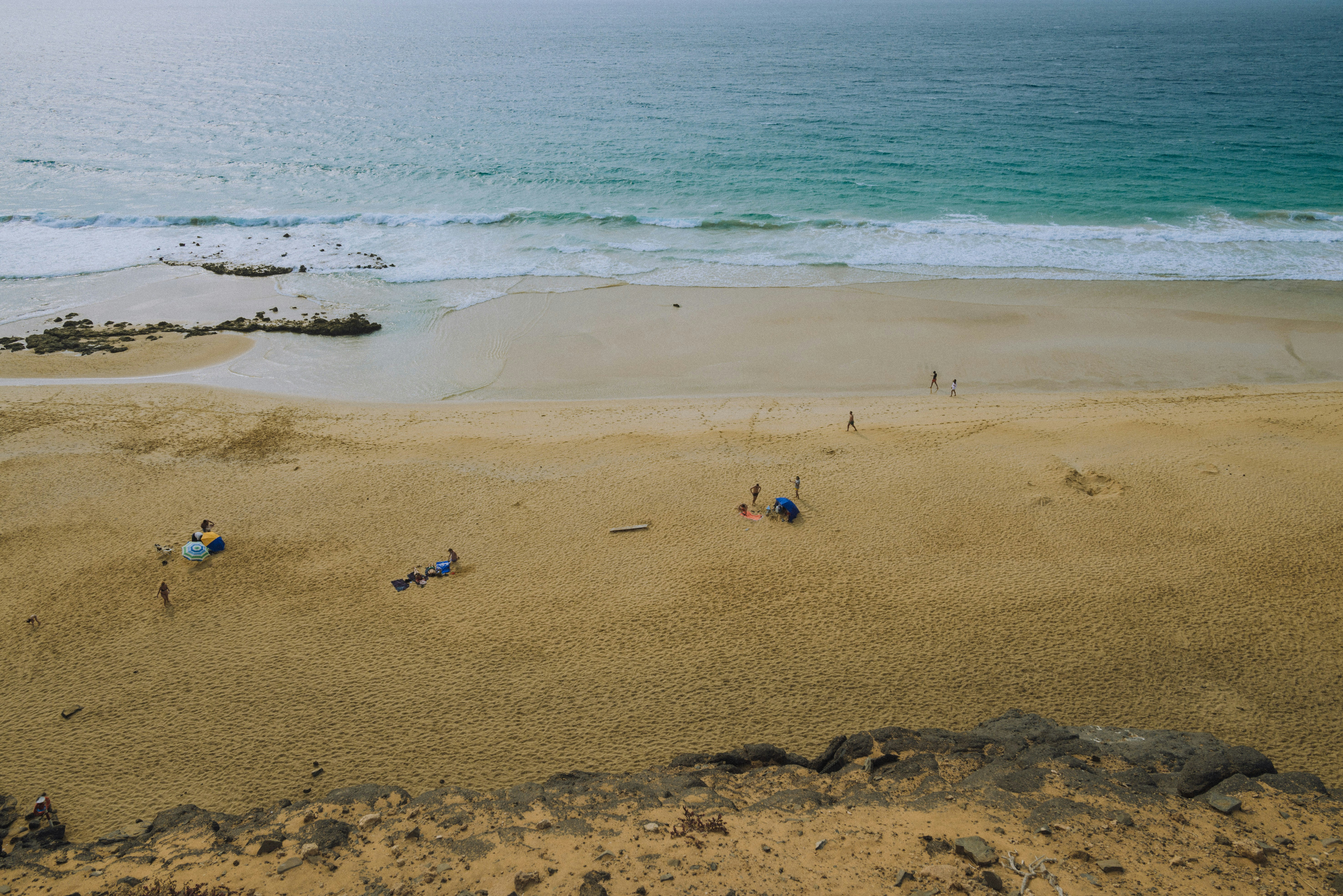 un groupe de personnes debout au sommet d’une plage de sable