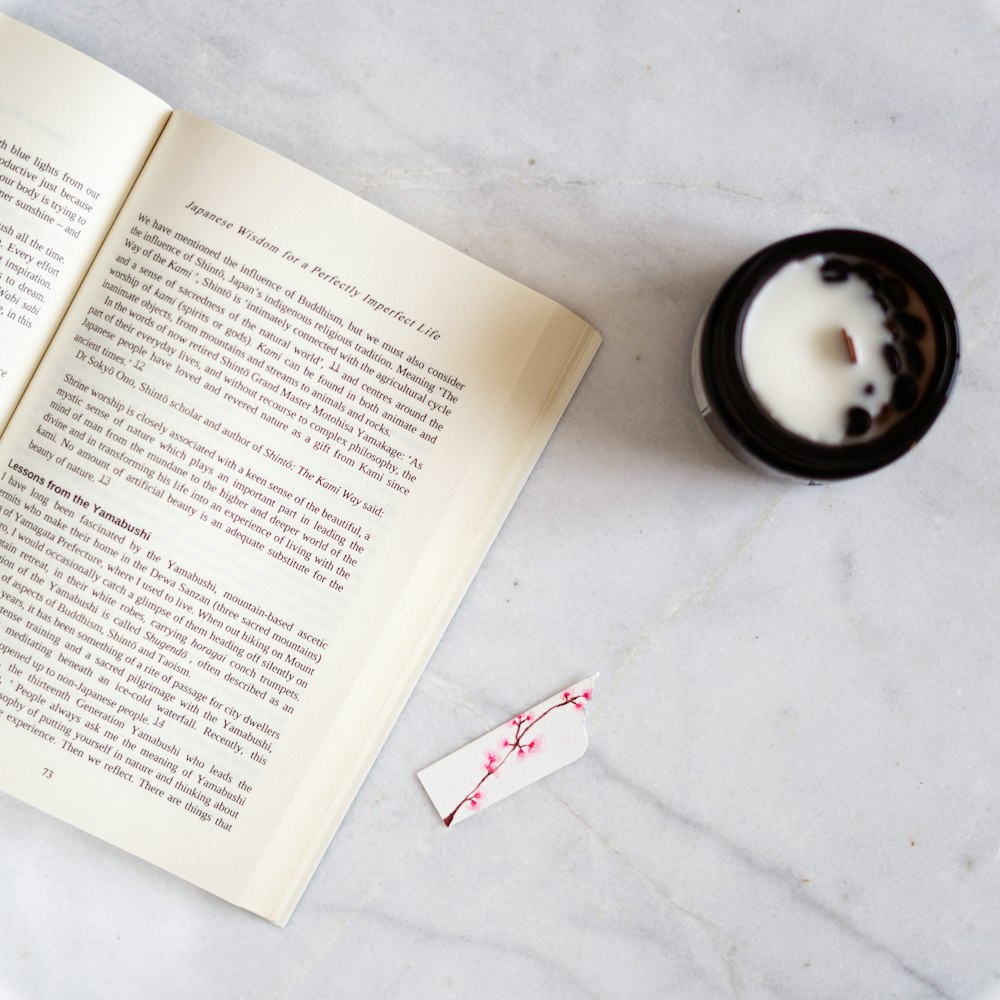 an open book next to a candle on a table