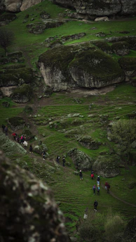 A group walking along a lush green trail with Bekal Fort visible in the distance.