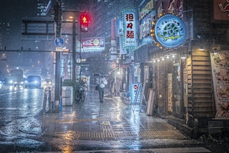 A moody nighttime street scene in Tokyo with glowing neon signs reflecting on wet pavement under a gentle rain.