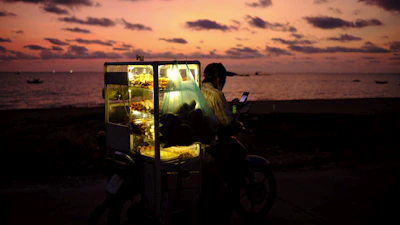 A striking vintage Hindustan Motors Ambassador transformed into a glowing fire-grilled street food cart at dusk.
