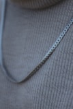 Layered silver and gold necklaces resting on a soft linen fabric background