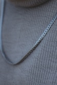 Close-up of a stainless steel necklace with delicate chain links draped on a wooden surface.