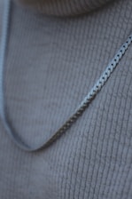 Close-up of a sleek silver necklace resting on a black velvet background.