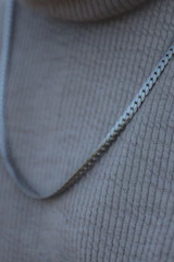 Close-up of a delicate gold necklace resting on a soft white fabric background.