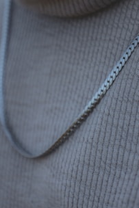 Close-up of a sparkling silver necklace with intricate details on a soft fabric background.