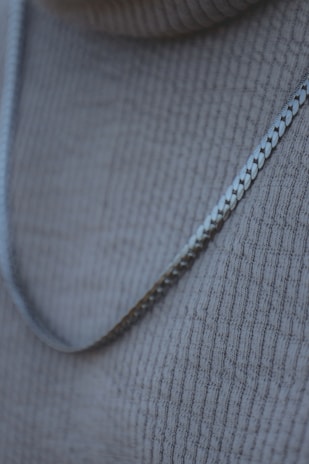 Close-up of a sleek silver necklace resting on a black velvet background.