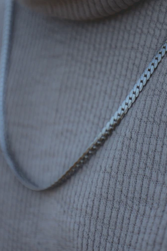 Close-up of a delicate handmade silver necklace resting on natural linen fabric.