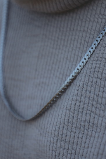A close-up of a delicate gold necklace resting on a soft fabric.