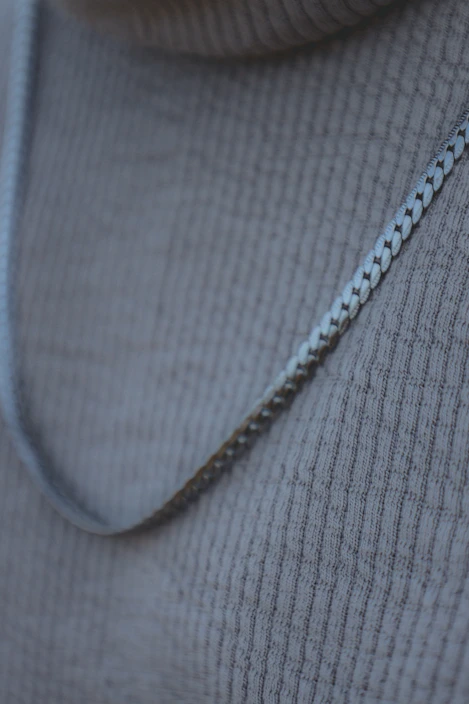 Close-up of a stylish silver necklace displayed on a dark textured surface