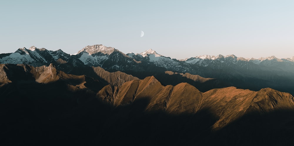 a view of a mountain range with a moon in the sky