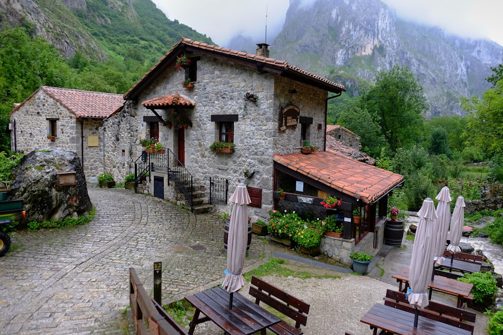 a stone building with tables and umbrellas in front of it