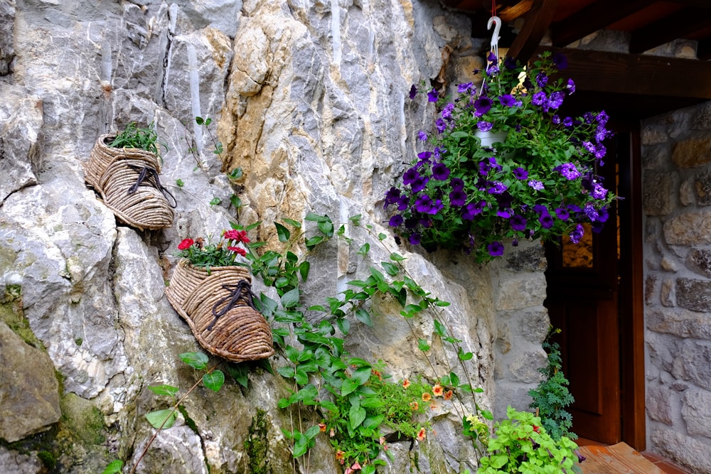 two baskets of flowers are hanging on a rock wall