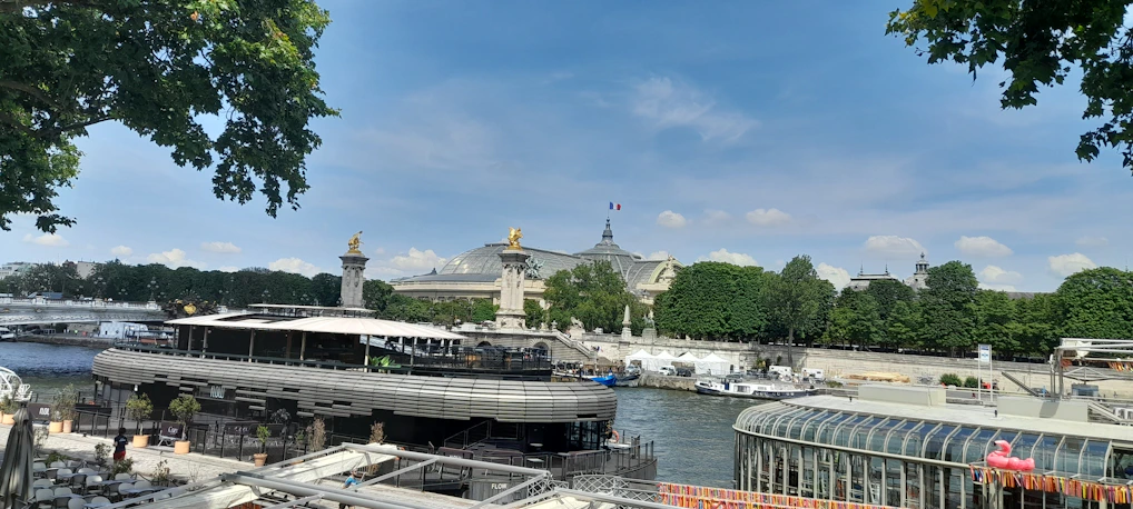 A sunny riverside view with a small dock and boats on the Garonne river in Portet-sur-Garonne.
