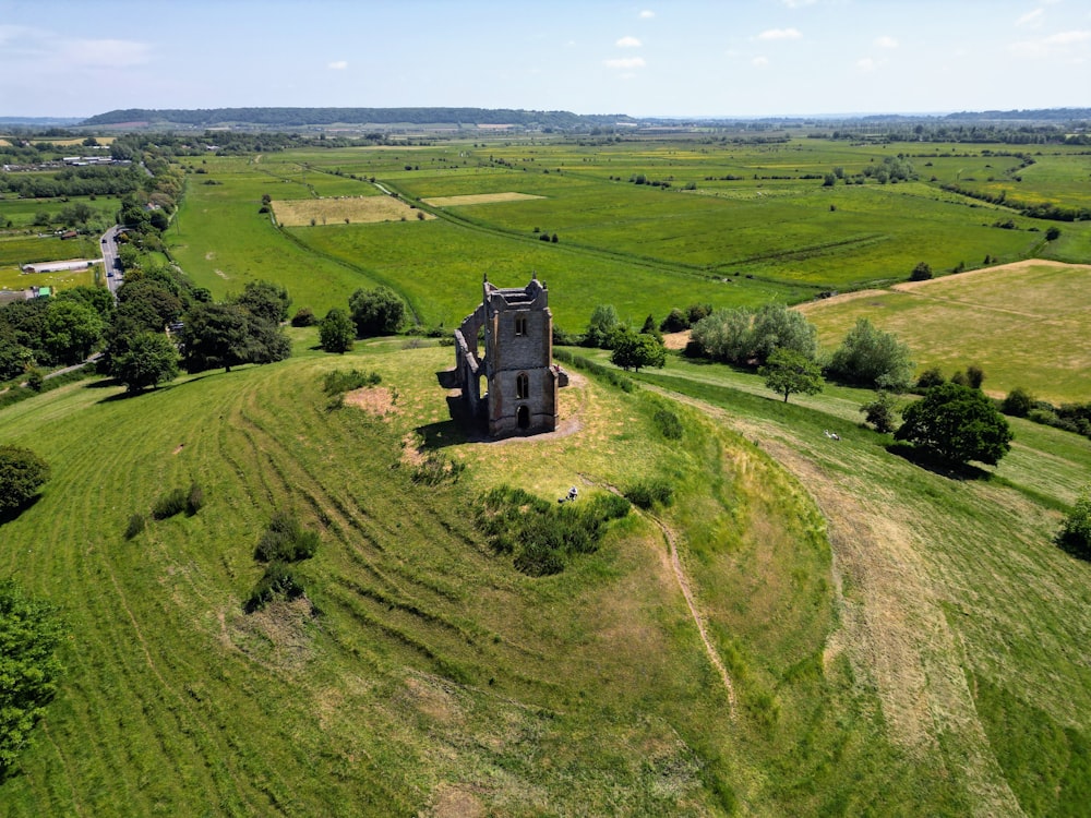an aerial view of an old building in a green field