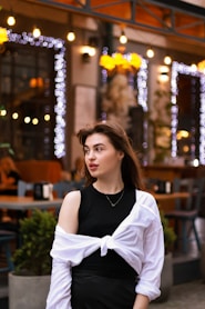 a woman standing outside of a restaurant wearing a black and white dress