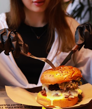 a woman holding a fork and knife over a hamburger