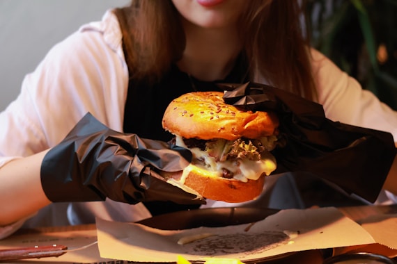 a woman sitting at a table with a sandwich in her hand
