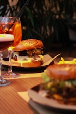 Close-up of a colorful plate with a burger, fries, and a soft drink on a wooden table.