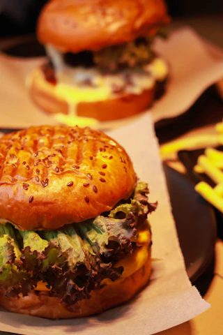 Close-up of a freshly made burger with melted cheese and crispy fries on the side.