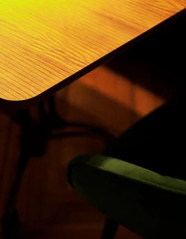 A cozy furniture store corner with wooden chairs and a small table bathed in warm light.