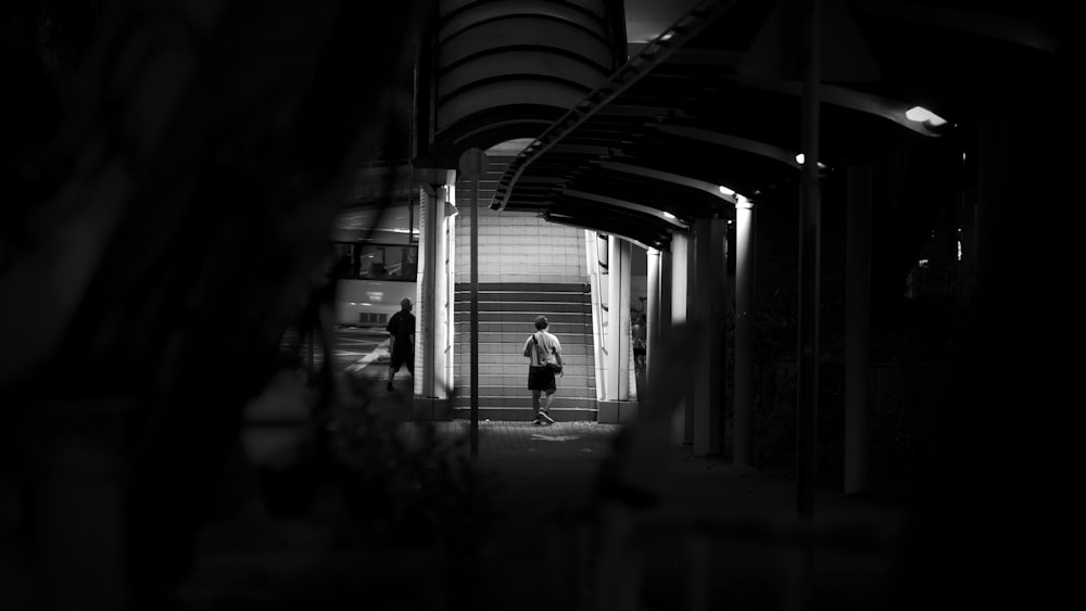 a black and white photo of a person walking down a hallway