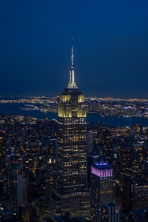 A nighttime view of a corporate glass building illuminated against a deep navy sky.
