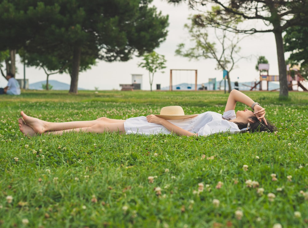 a woman laying in the grass with a hat on her head