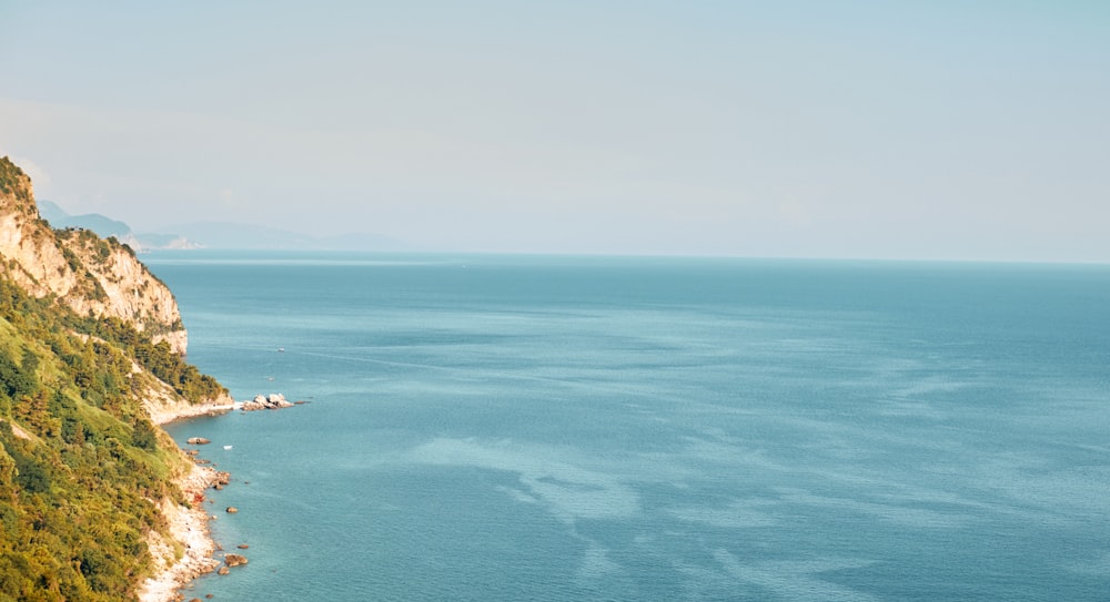 a large body of water sitting next to a lush green hillside