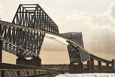 Engineer examining a steel bridge structure with measuring tools on a sunny day
