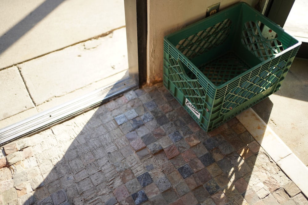 a green basket sitting next to a door