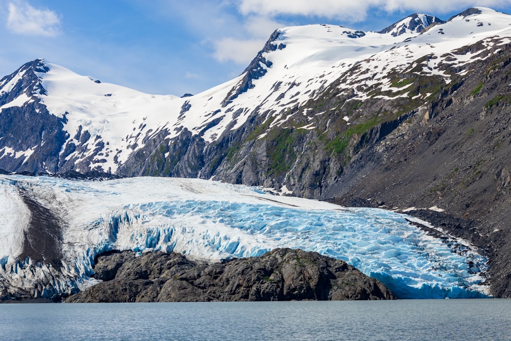 a large glacier with snow covered mountains in the background