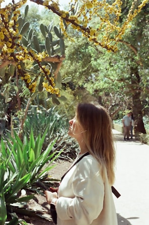 a woman standing in front of a tree with yellow flowers