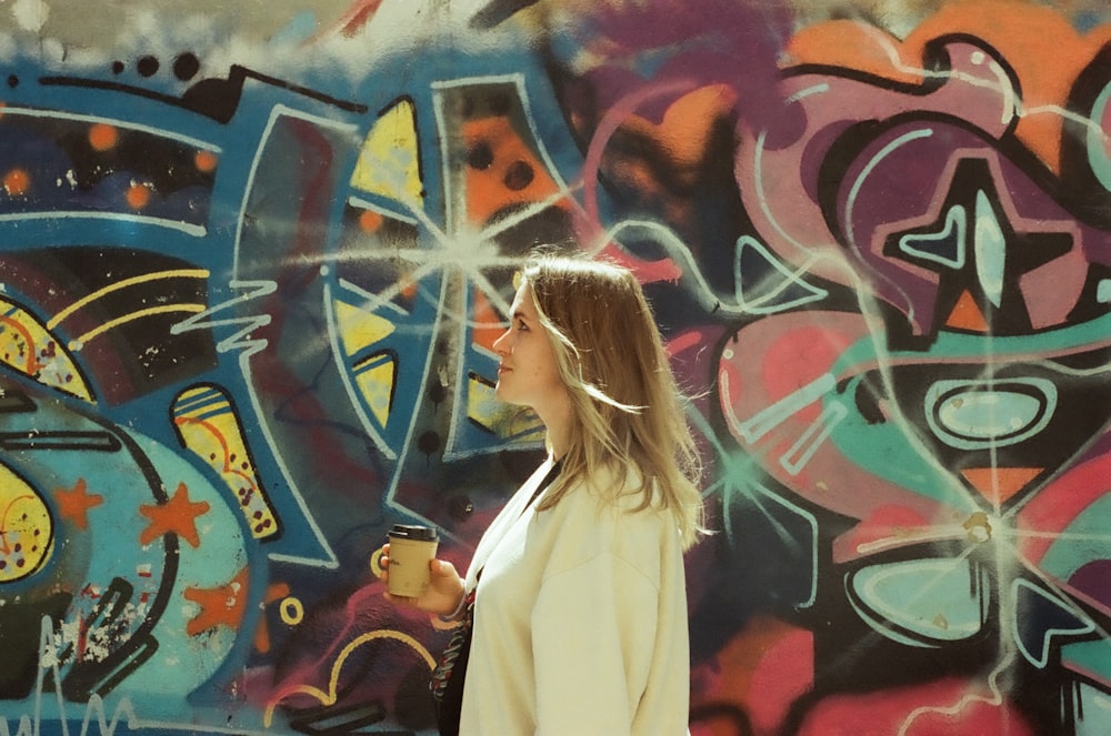 a woman standing in front of a wall covered in graffiti