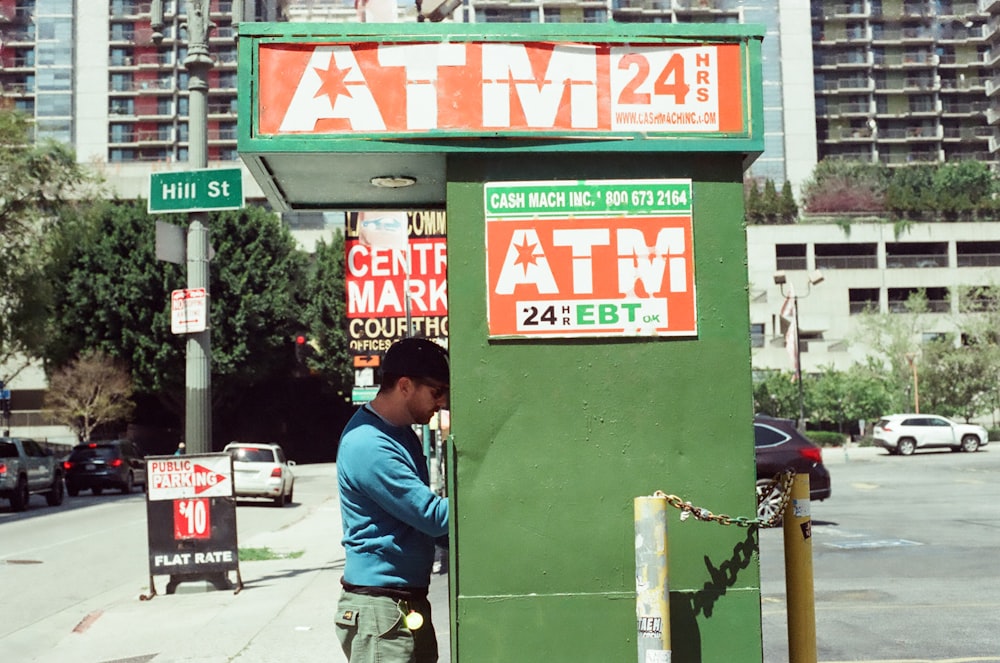 a man standing next to a green atm machine