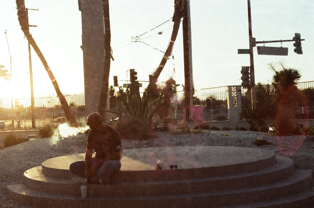 a woman sitting on a cement step next to a plant