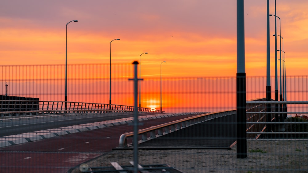 the sun is setting behind a fenced in area