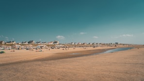 A clean beach with people enjoying the sun.