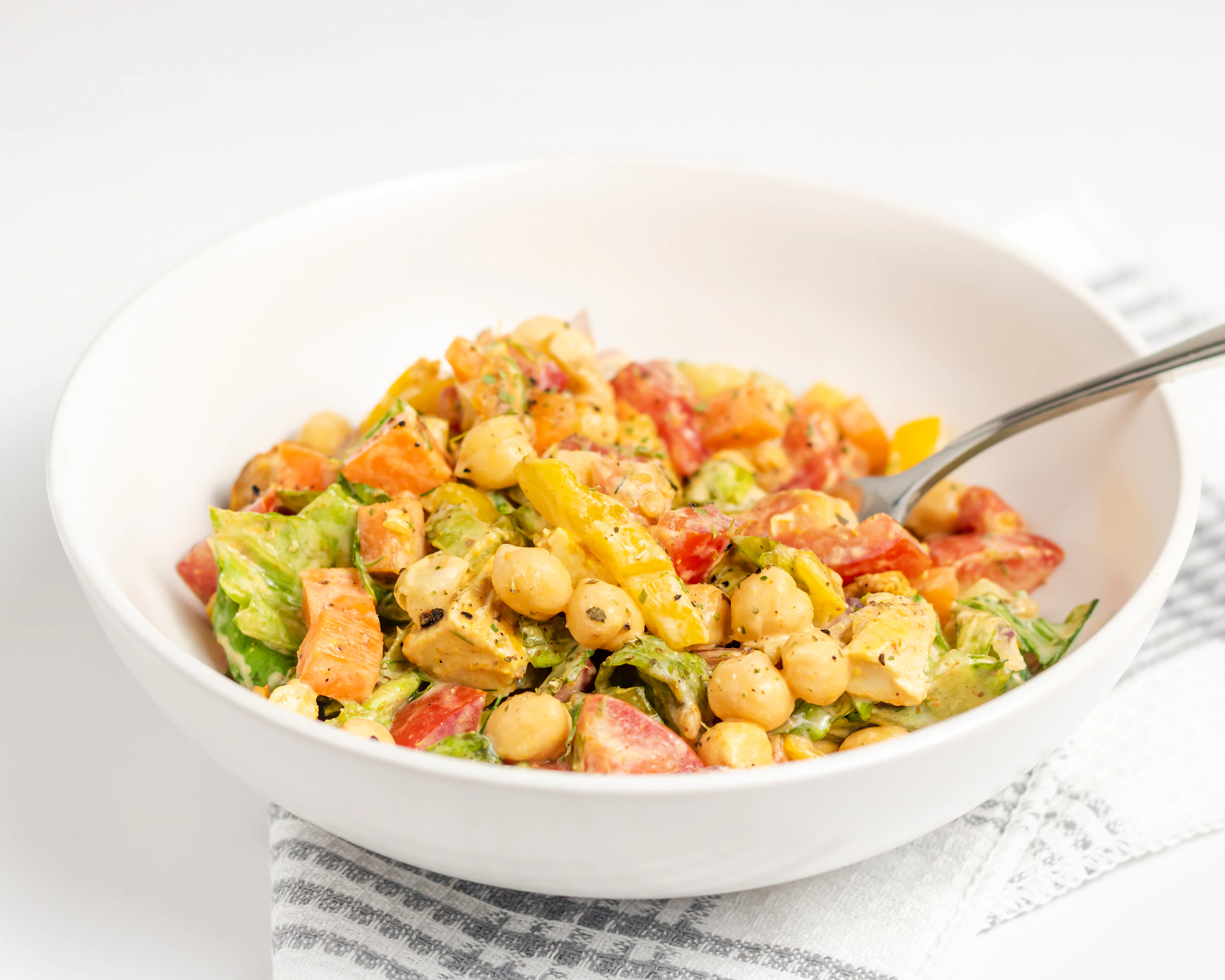 Salade de pois chiches, de poivron et de tomate dans un bol blanc
