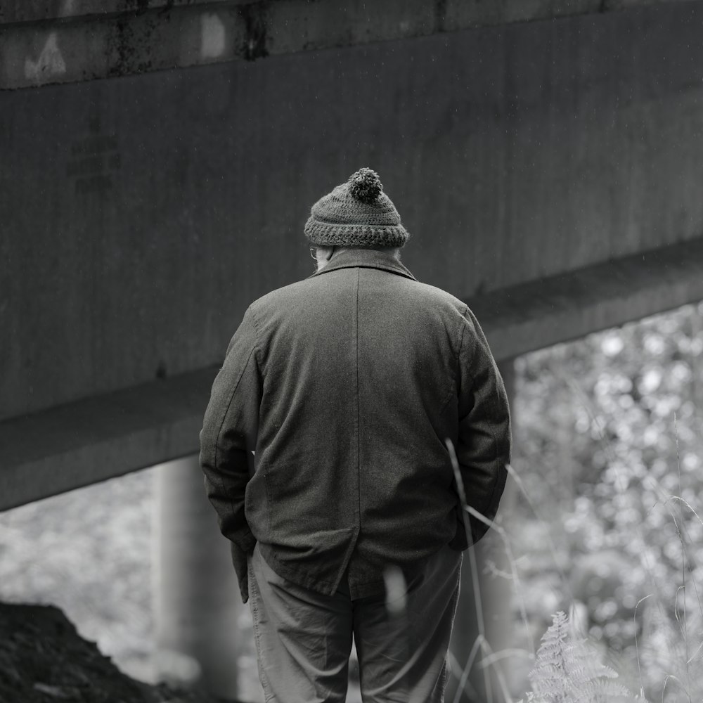 a man walking under a bridge with a hat on