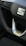 Close-up view of a car steering wheel displaying a prominent logo in the center. The steering wheel features a sporty design with a silver trim and is accompanied by buttons for various controls. The stitching on the wheel is visible, indicating a detailed and refined finish.