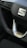 Close-up view of a car steering wheel displaying a prominent logo in the center. The steering wheel features a sporty design with a silver trim and is accompanied by buttons for various controls. The stitching on the wheel is visible, indicating a detailed and refined finish.