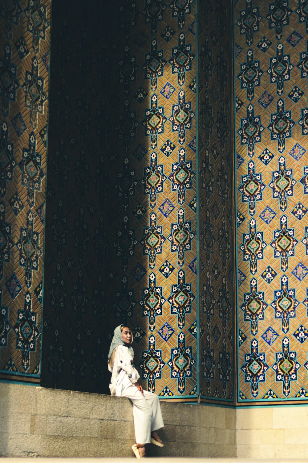 a woman sitting on a step in front of a wall