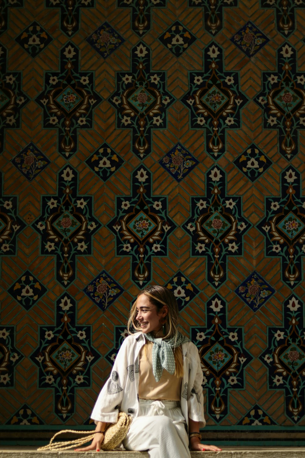 a woman sitting on a ledge in front of a wall