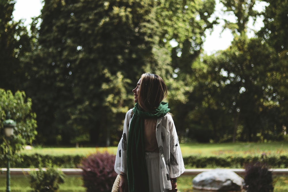 a woman walking in a park with a green scarf around her neck