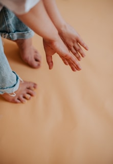 Close-up of hands gently touching the floor during a mindful movement session, highlighting calm and focus.