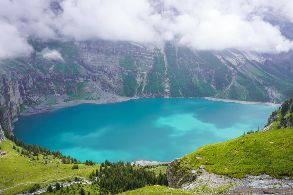 a large blue lake surrounded by mountains and clouds