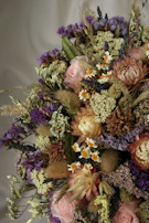 A charming mix of wildflowers and roses in a handcrafted bouquet for weddings.